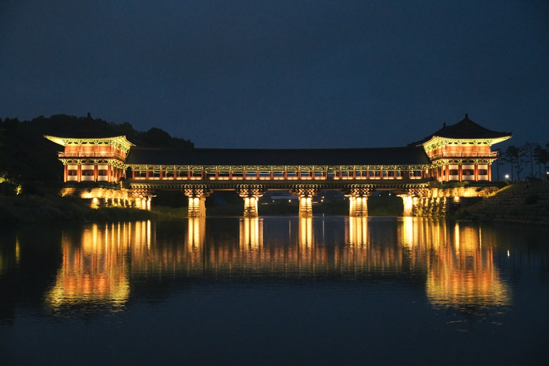 A lit covered bridge in Gyeongju reflected in still water after dark, the kind of night scene the city's sites are visited for